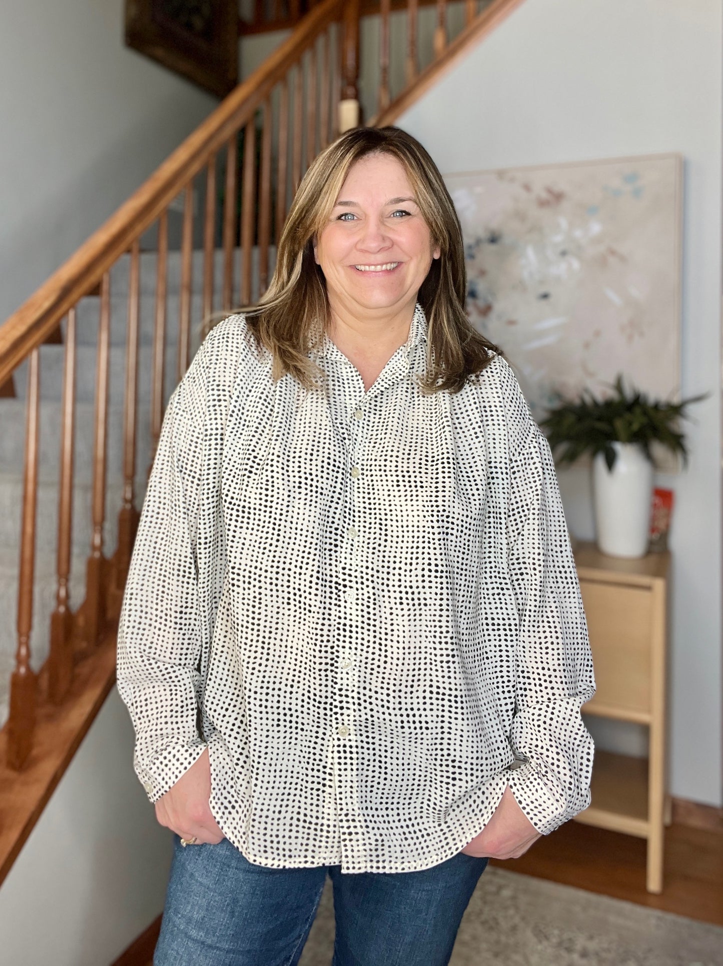 Woman standing in a home setting with a staircase in the background