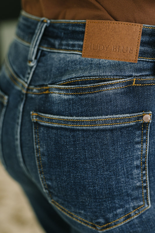 Close-up of blue jeans with a brown leather patch displaying 'JUDY BLUE'.