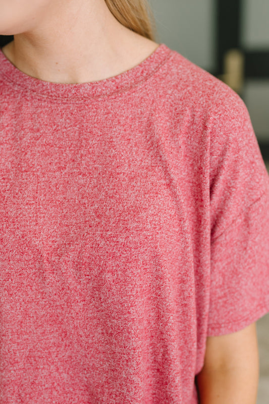 Close-up of a person wearing a heathered pink short-sleeve crewneck t-shirt.