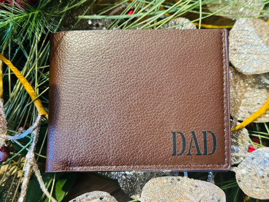 Brown leather cardholder with 'DAD' engraving on a decorative background