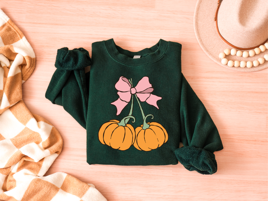 Green sweatshirt with pumpkin and bow design on a wooden surface