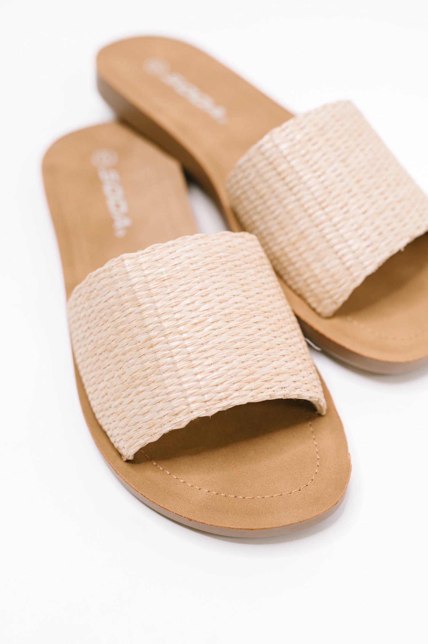 A pair of women's slide sandals with wide woven beige straps and tan footbeds, shown on a clean white background.