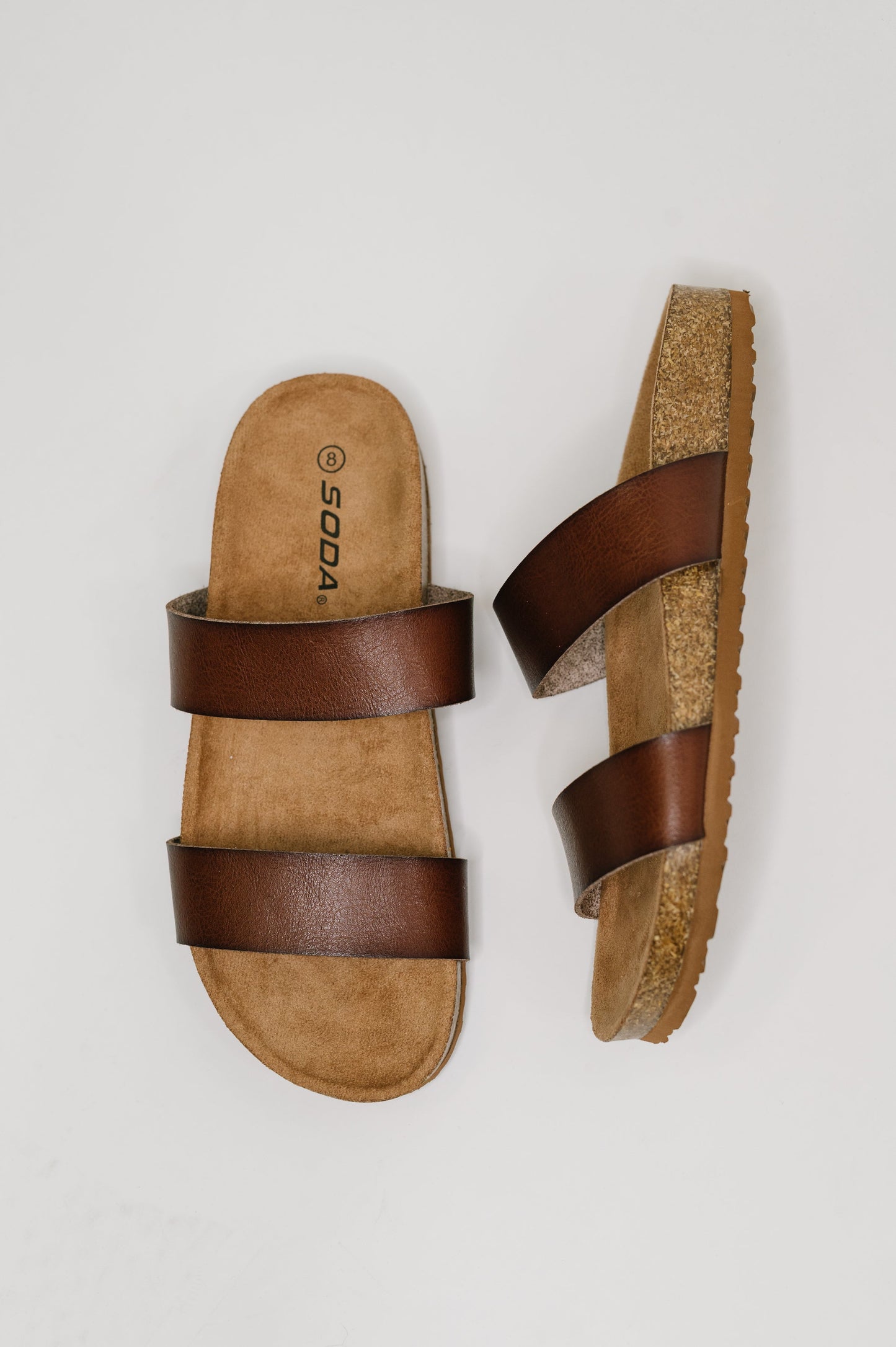 Pair of brown sandals with cork sole on a light gray background