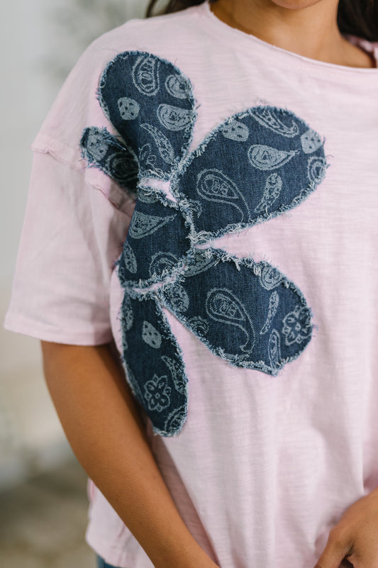 Pink t-shirt with a blue paisley butterfly design on a blurred background