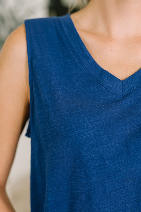 Close-up of a person wearing a blue sleeveless top with a blurred background