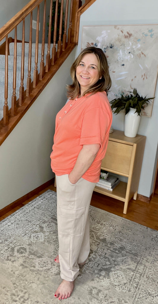 Woman standing in a home setting with a staircase and decorative items in the background