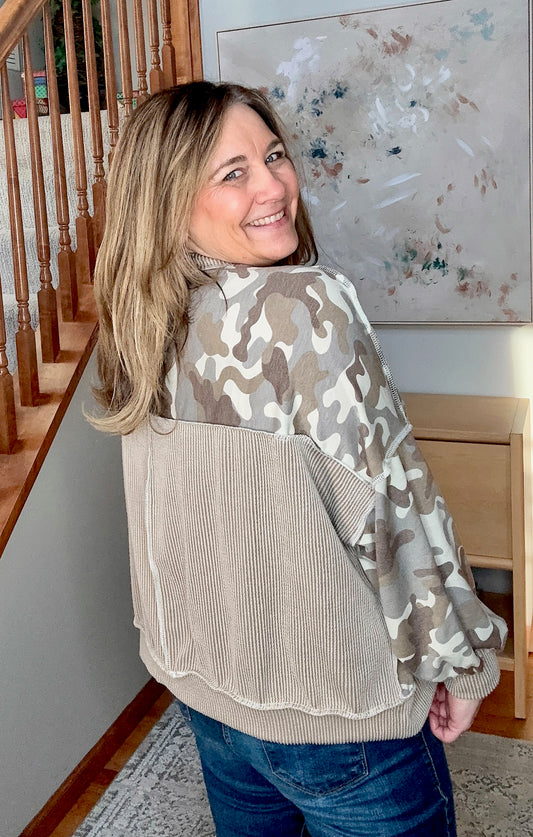 Woman wearing a camouflage and beige sweater in a home setting