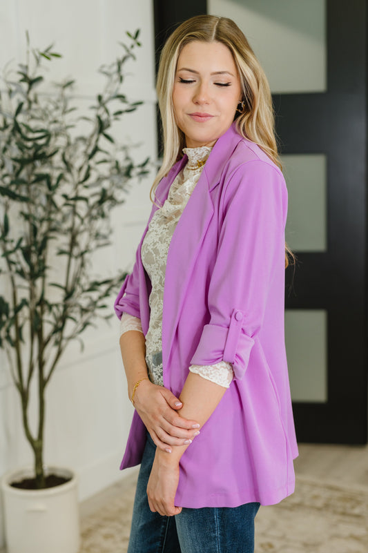 Woman wearing a purple jacket in an indoor setting with a plant in the background