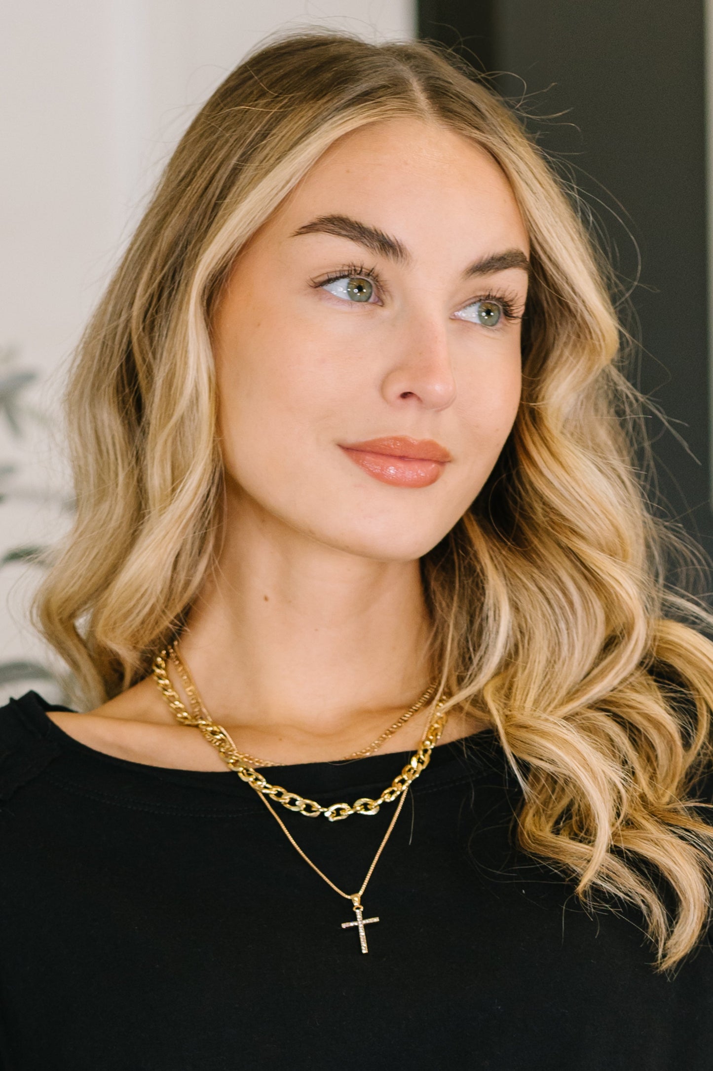 Woman wearing gold necklaces with a neutral background