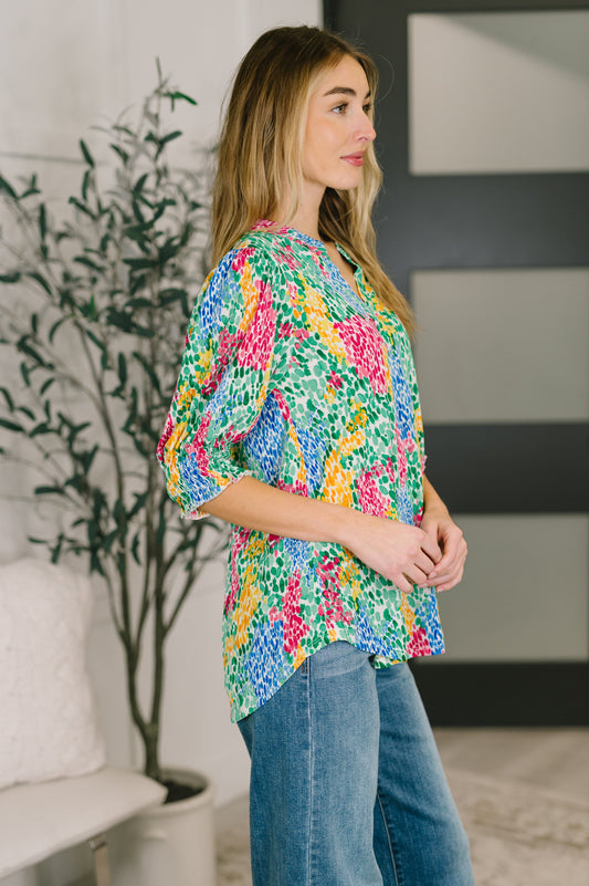 Woman wearing a colorful floral blouse and blue jeans in an indoor setting.