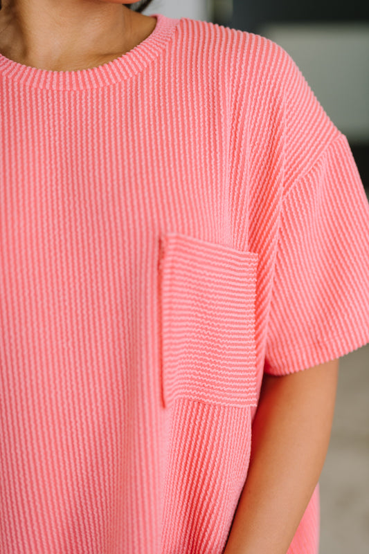 Close-up of a person wearing a pink textured dress with a pocket.