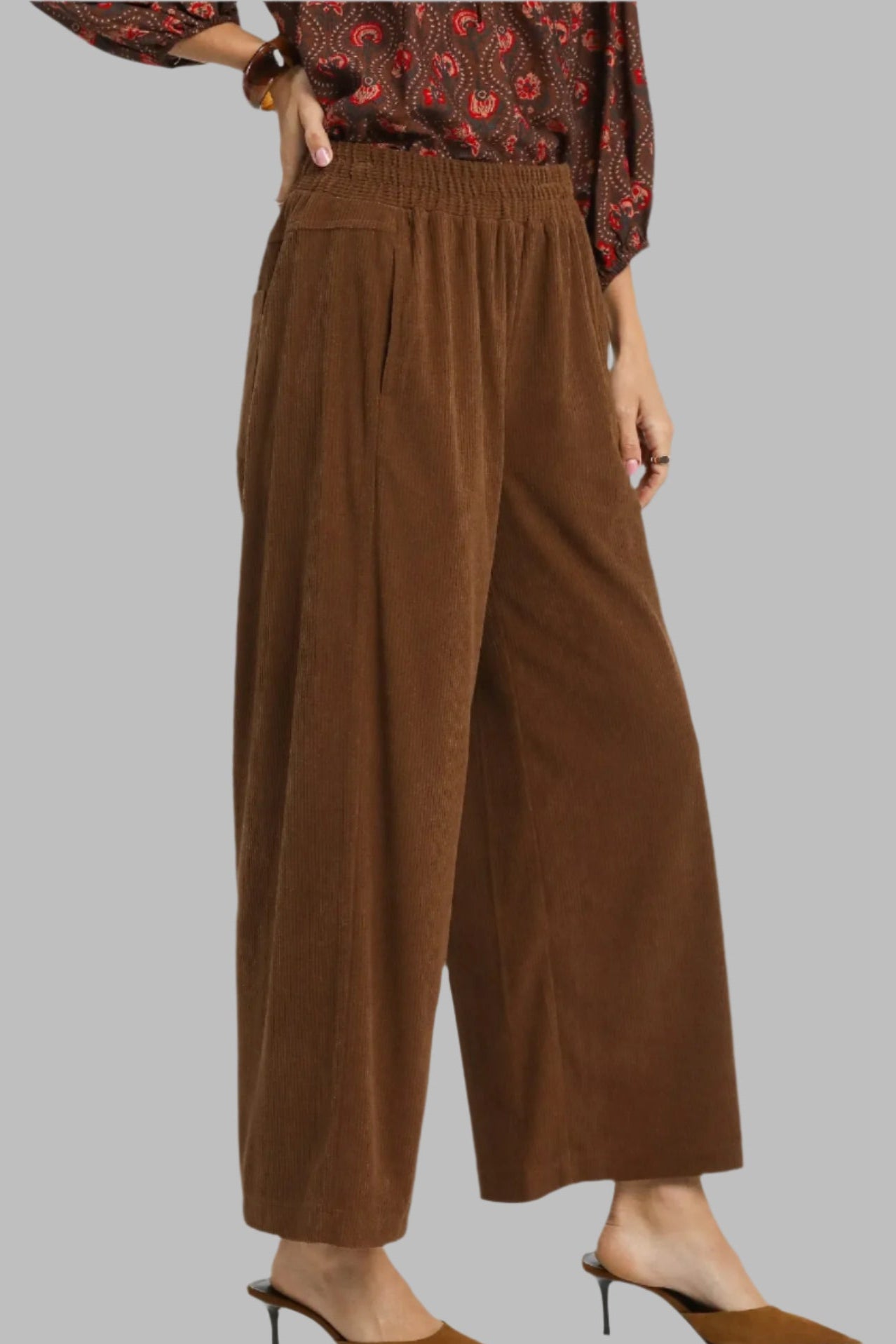 Brown wide-leg pants worn by a person on a gray background