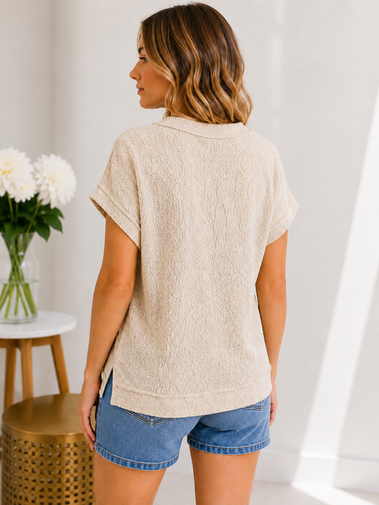 Woman wearing a beige textured top and blue shorts in a bright room.