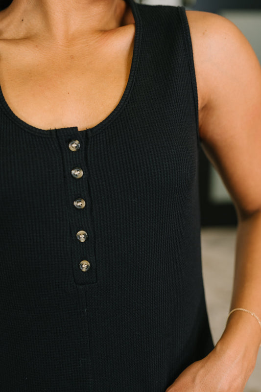 Black sleeveless top with button details on a blurred background