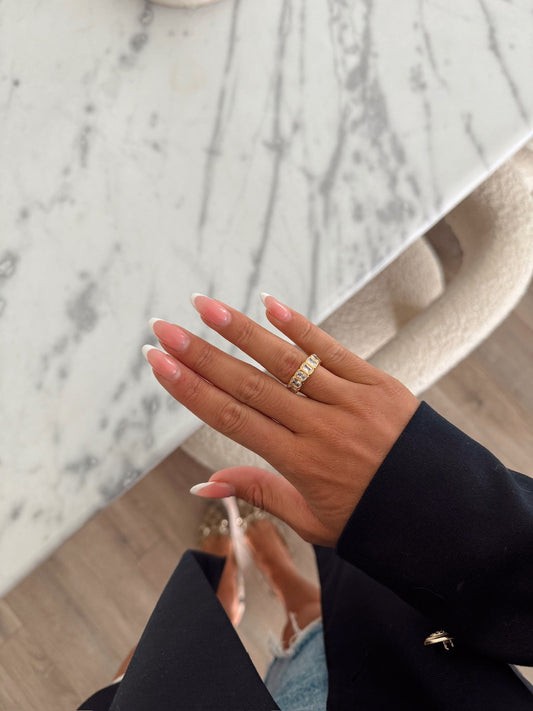 Hand wearing a gold ring with a marble background
