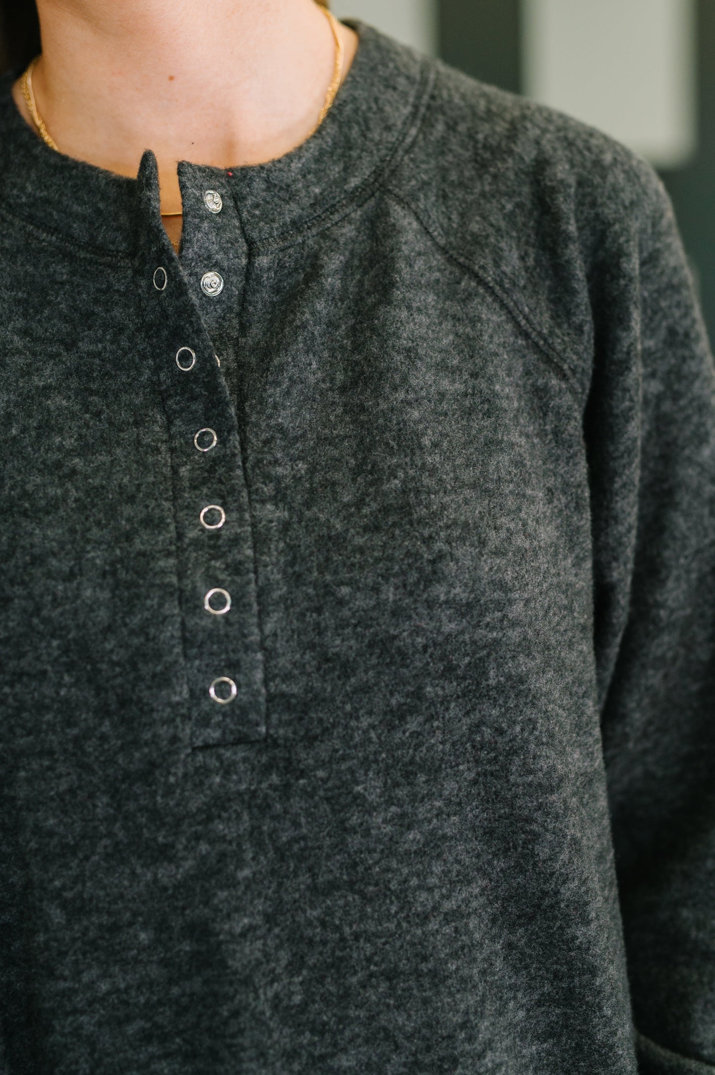 Close-up of a person wearing a black henley button-up shirt.