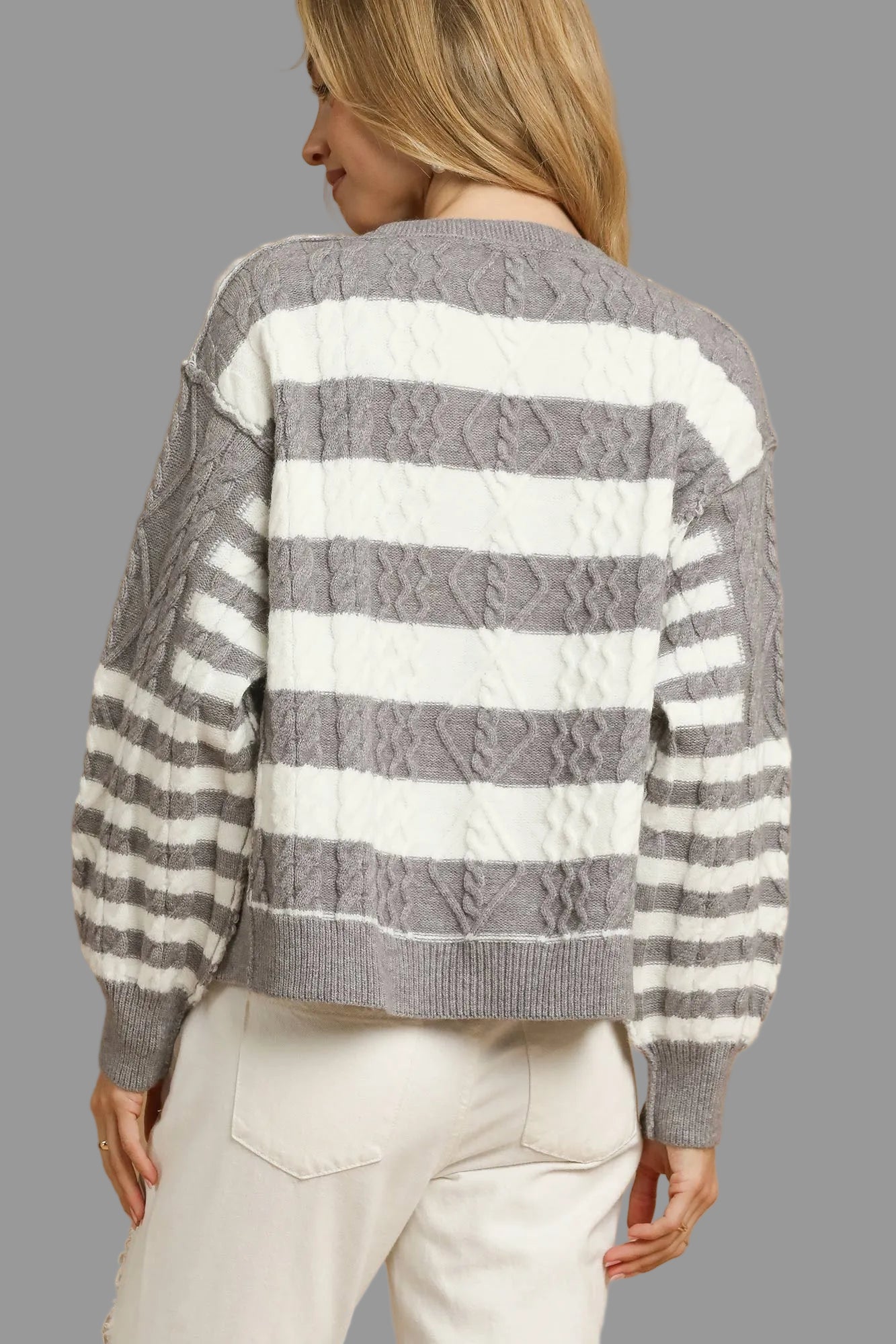 Woman wearing a gray and white striped button up cardigan sweater.
