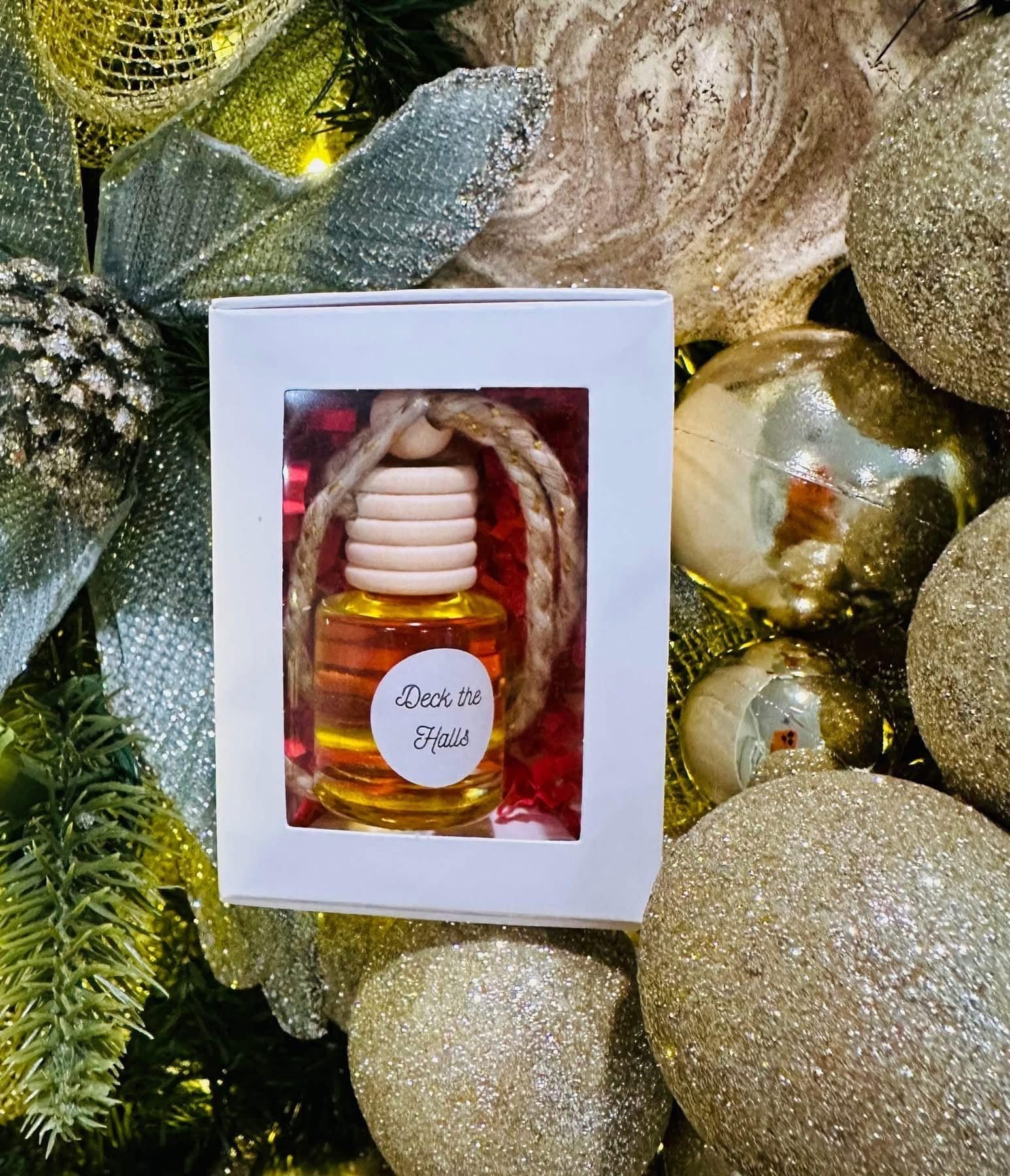 Decorative car diffuser bottle with a label in a box surrounded by festive ornaments