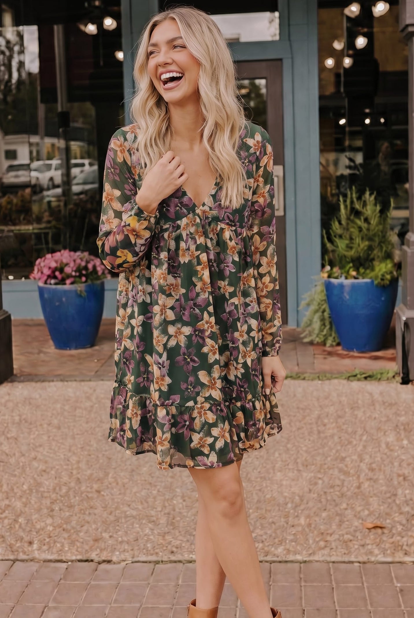 Woman in a floral dress laughing outdoors