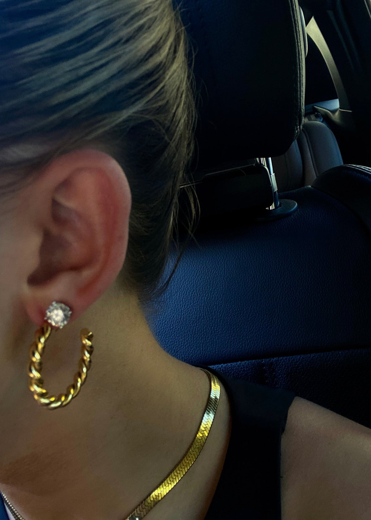 Close-up of an ear wearing gold hoop earrings with a blurred background