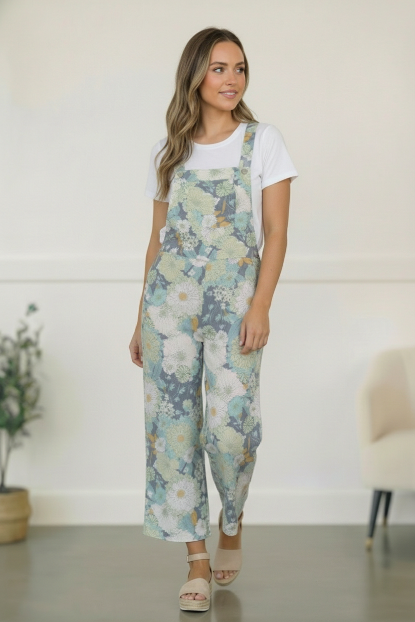 Woman wearing floral overalls and a white t-shirt in a minimal indoor setting