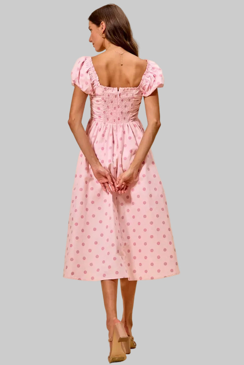 Woman wearing a pink dress with ruffled sleeves on a beige background