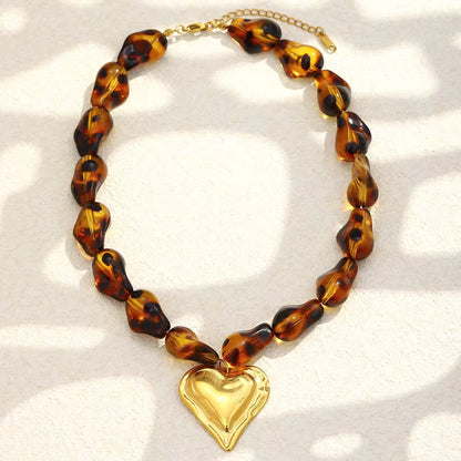 Tortoiseshell beaded necklace with a gold heart pendant on a white background