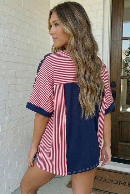Woman wearing a red and navy striped shirt with a blue side panel, standing in front of a door.