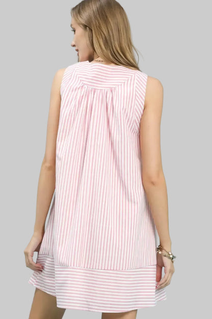 Woman wearing a pink and white striped dress against a light grey background