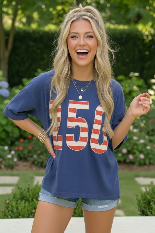 Woman wearing a blue t-shirt with '50' printed on it, standing outdoors.