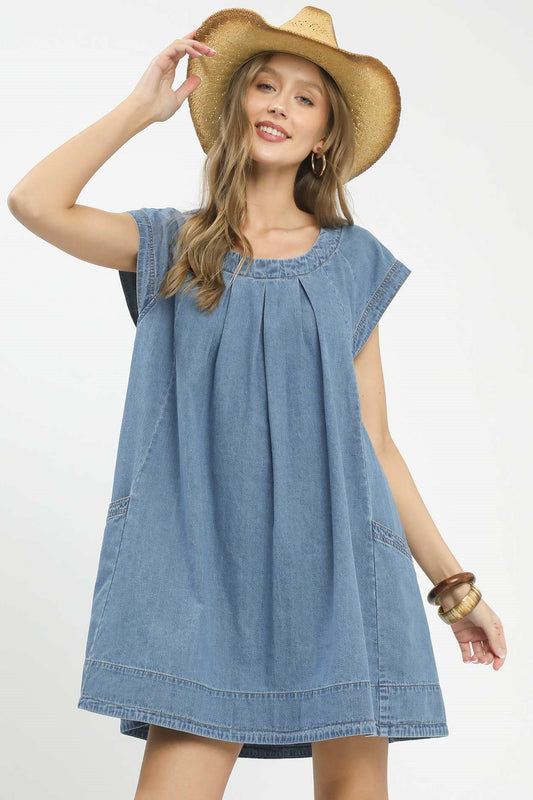 Woman wearing a denim dress and straw hat on a white background