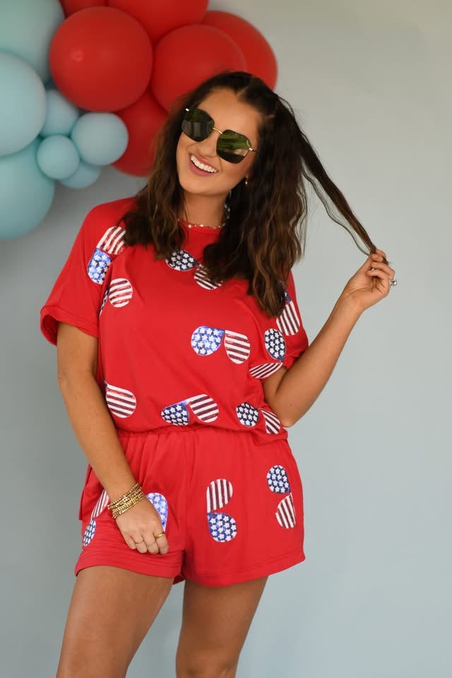 Woman wearing a red outfit with American flag patterns in front of balloons.