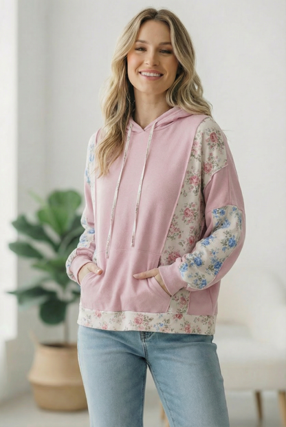 Woman wearing a pink hoodie with floral sleeves indoors