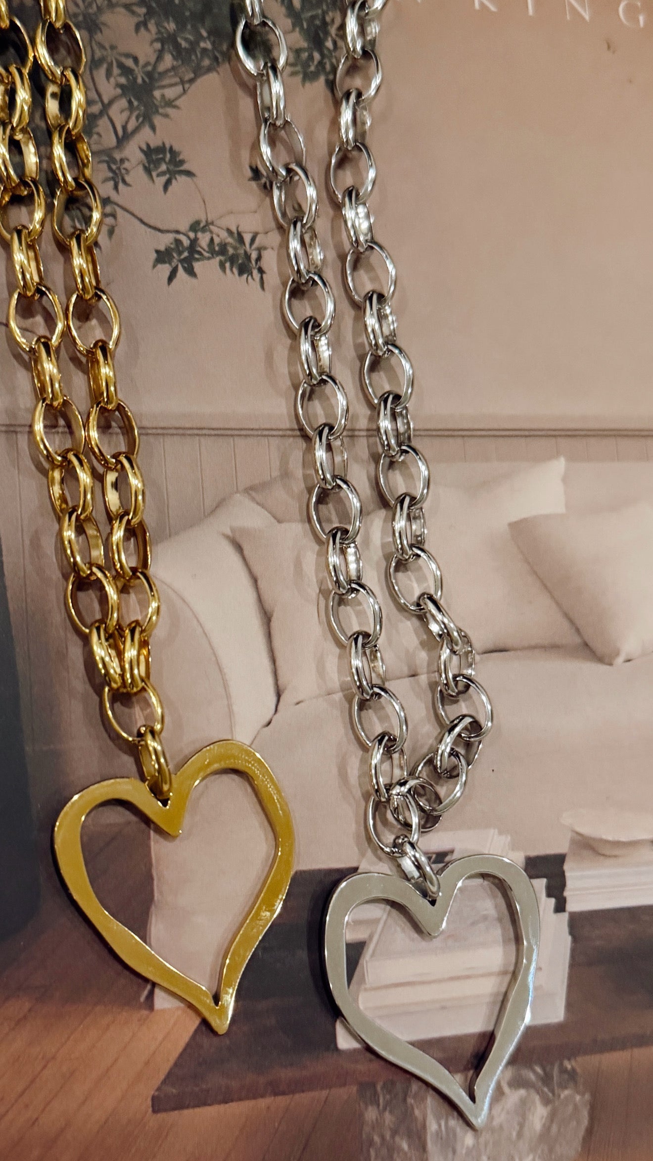 Two chain necklaces with heart pendants on a surface with a blurred background