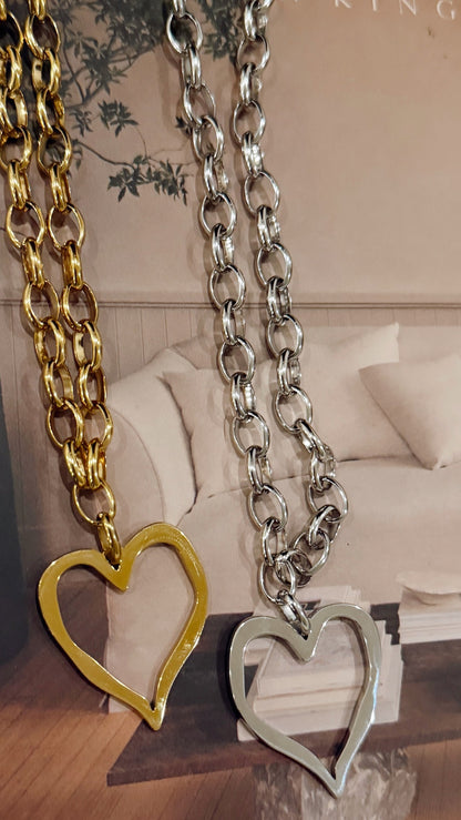 Two chain necklaces with heart pendants on a surface with a blurred background