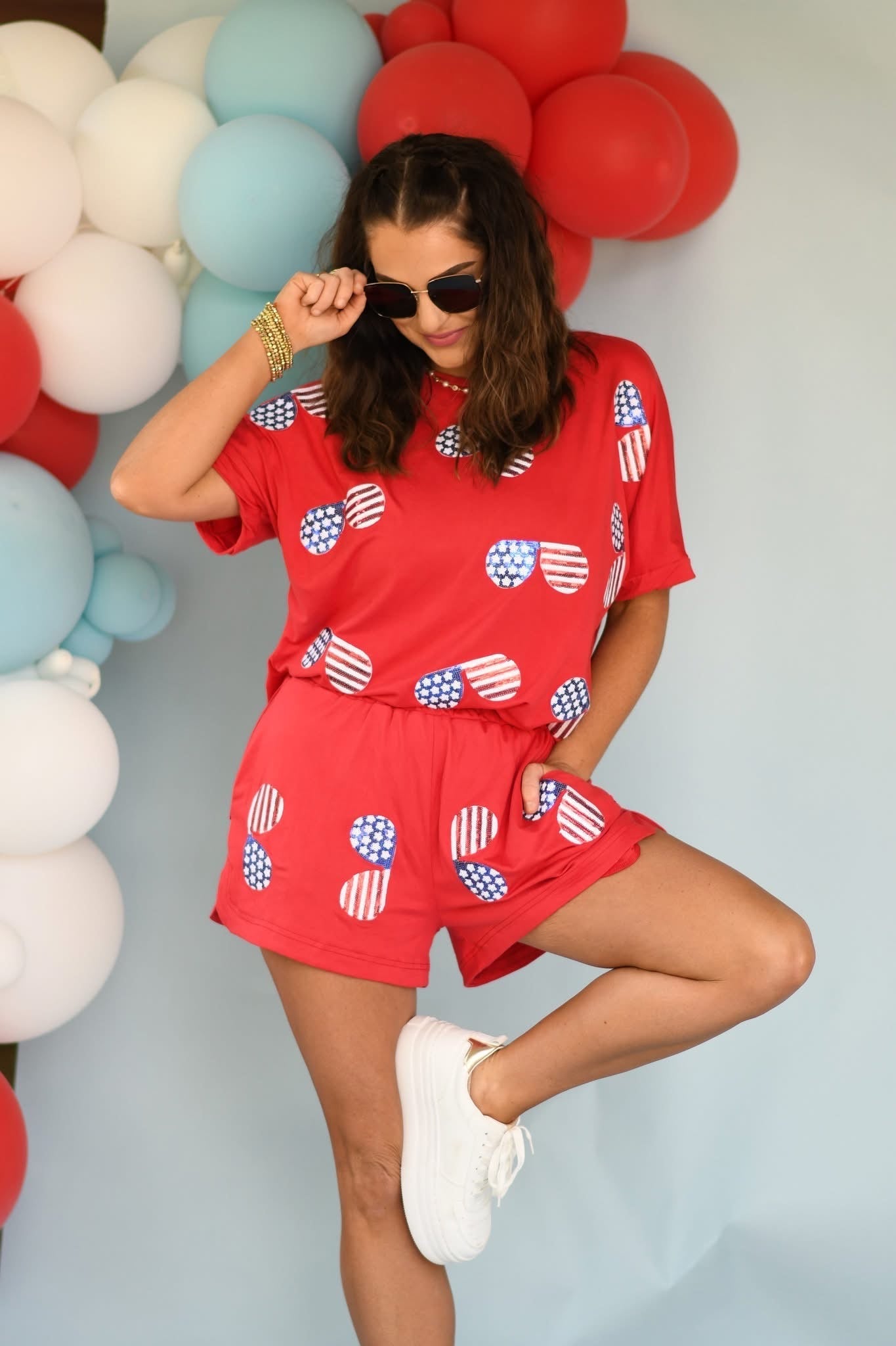 Woman in a red outfit with American flag patterns posing in front of balloons.