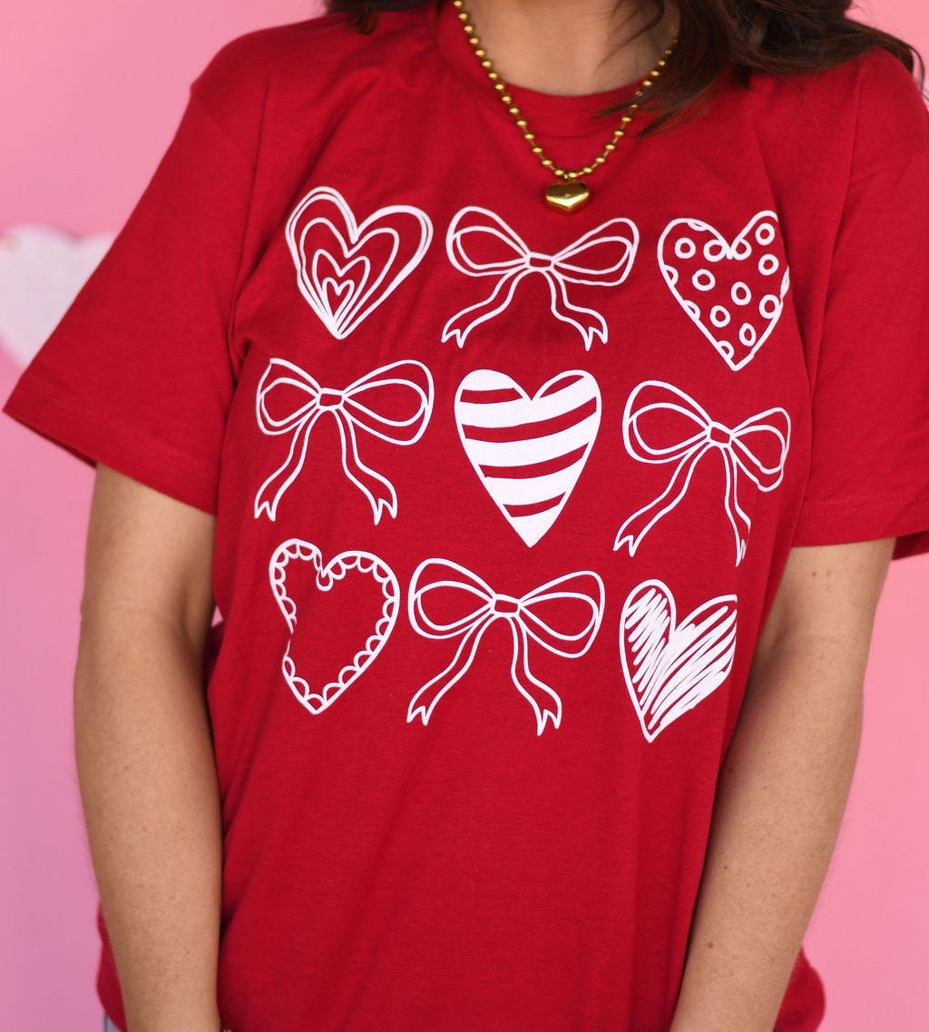 Red t-shirt with white heart and bow designs on a pink background