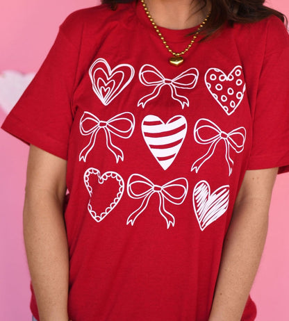 Red t-shirt with white heart and bow designs on a pink background