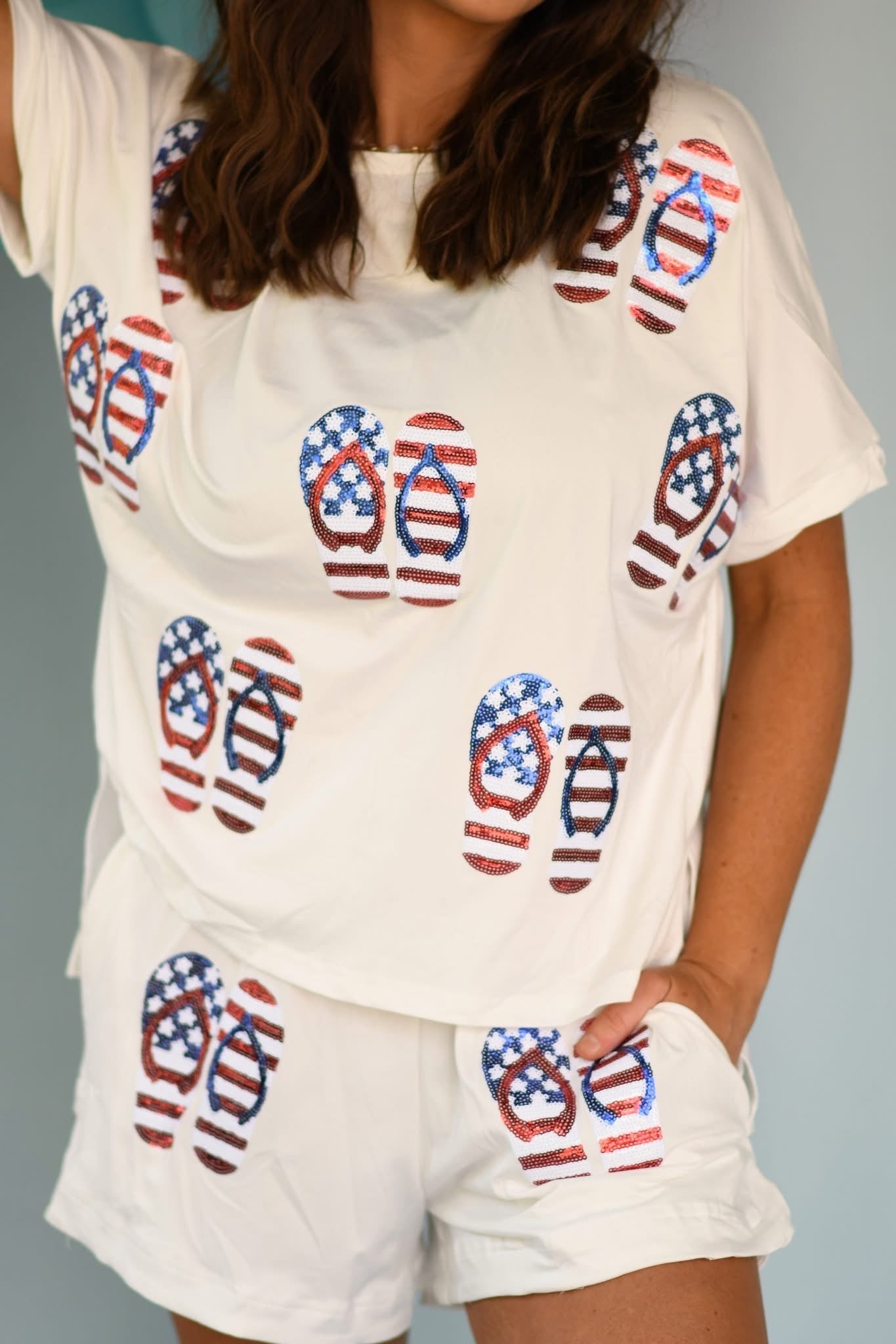 Person wearing a white outfit with American flag flip-flop pattern on a gray background
