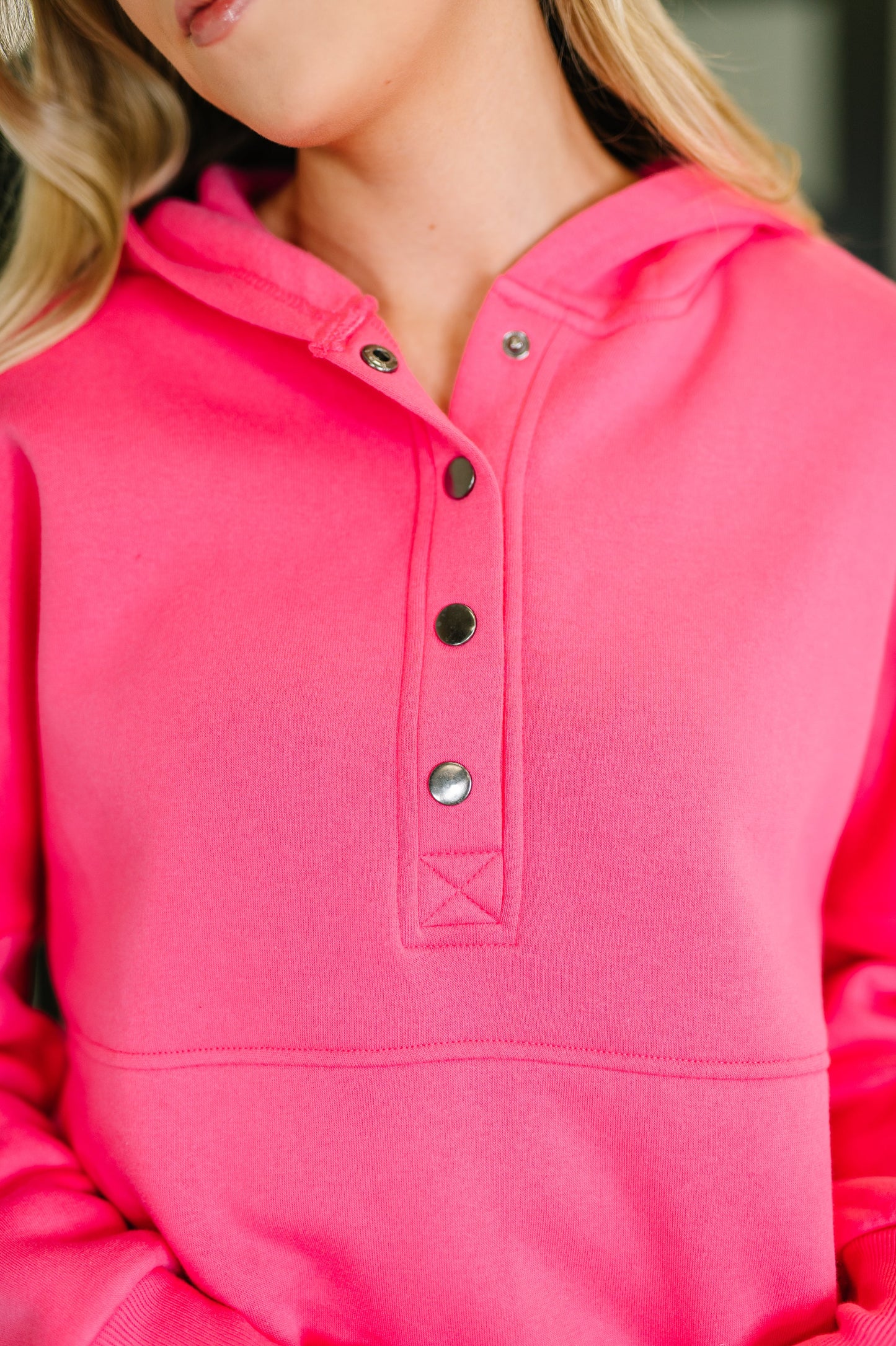 Close-up of a pink hoodie with button details