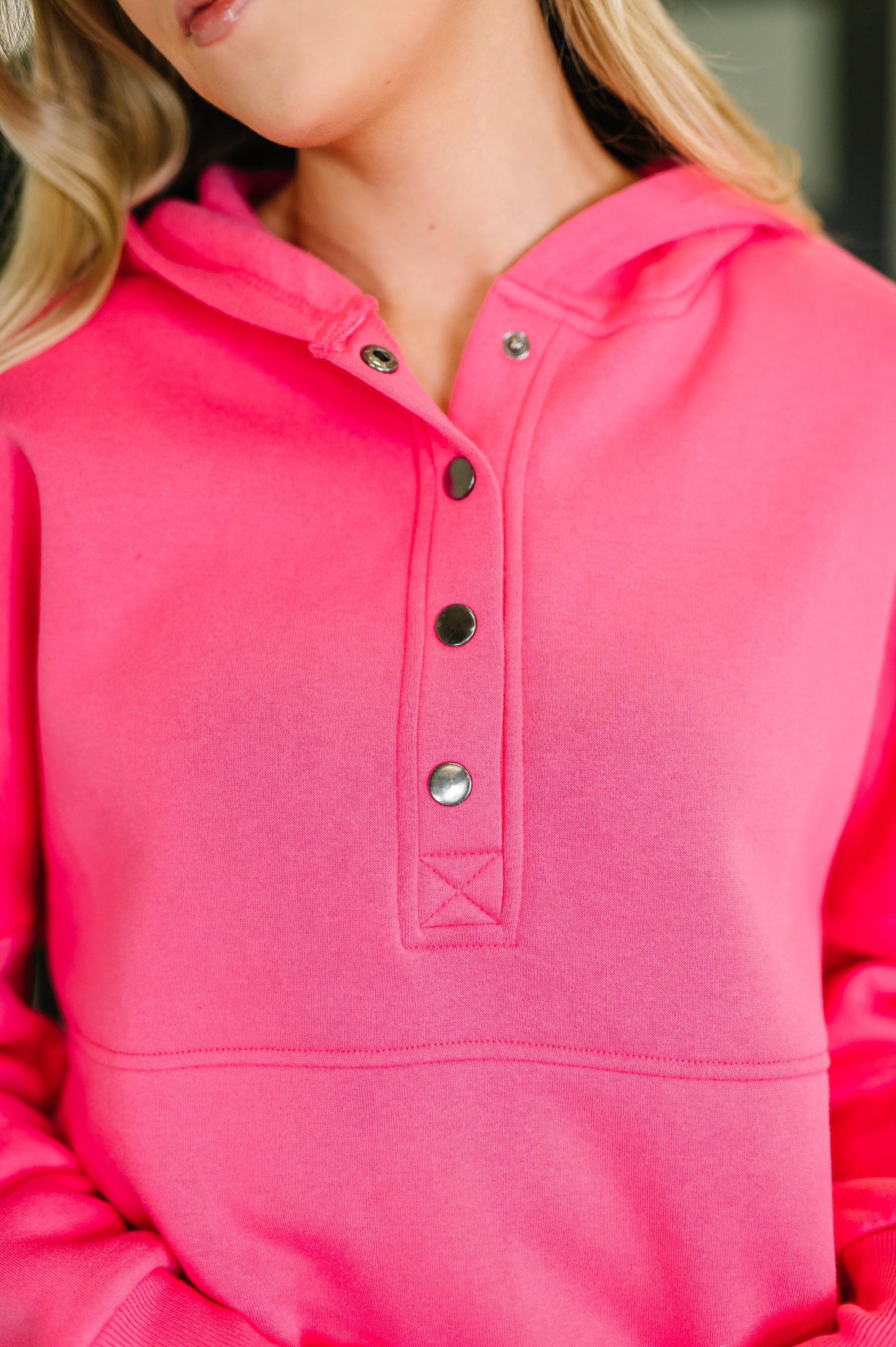 Close-up of a pink hoodie with button details
