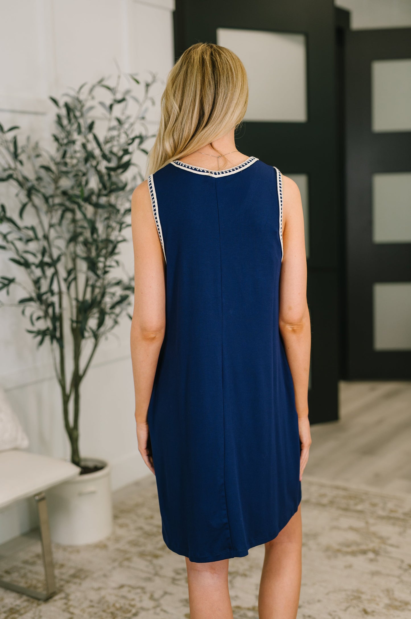 Woman wearing a blue dress with white trim in an indoor setting