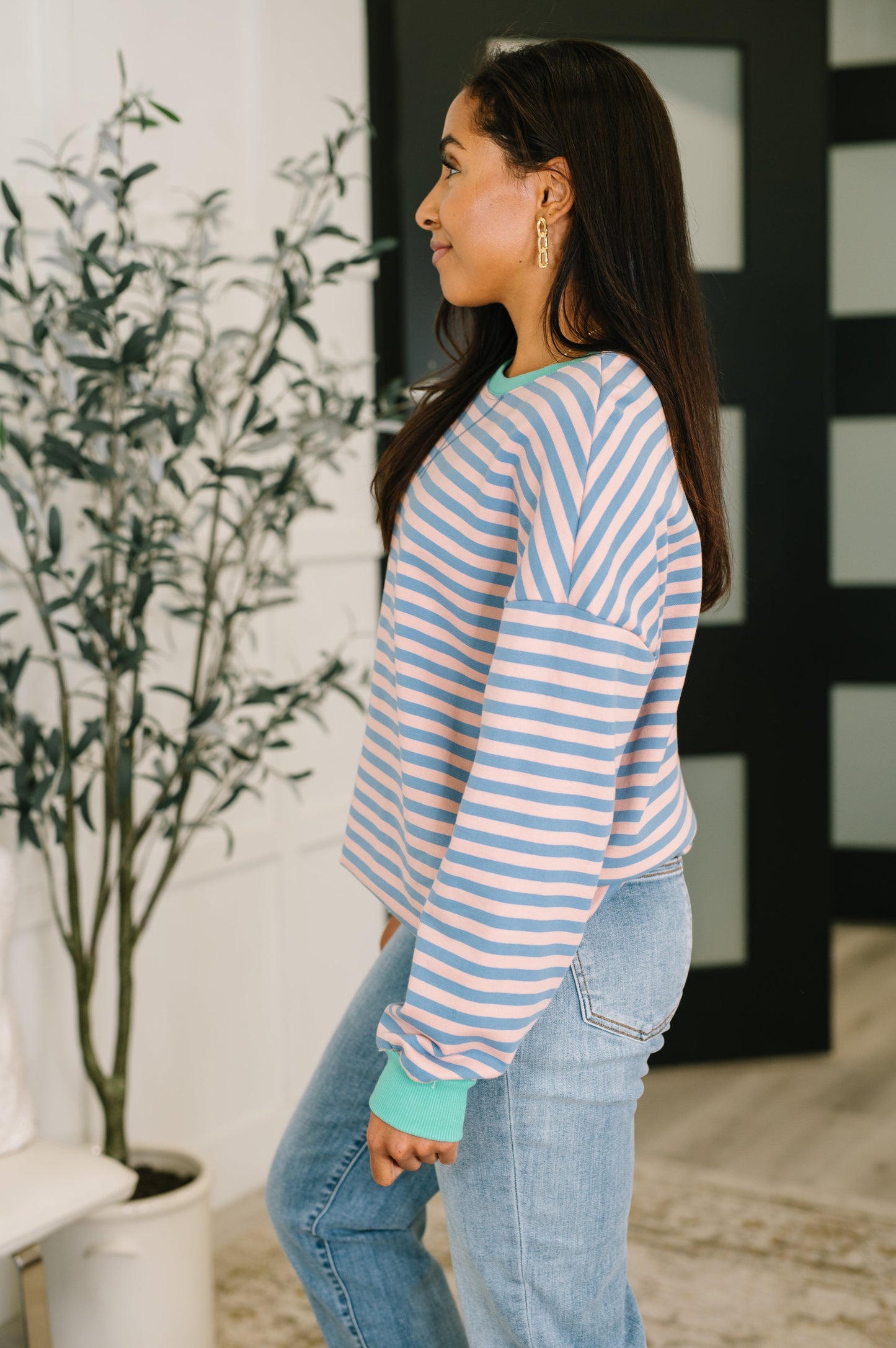 Woman wearing a blue and white striped sweater and jeans standing indoors.