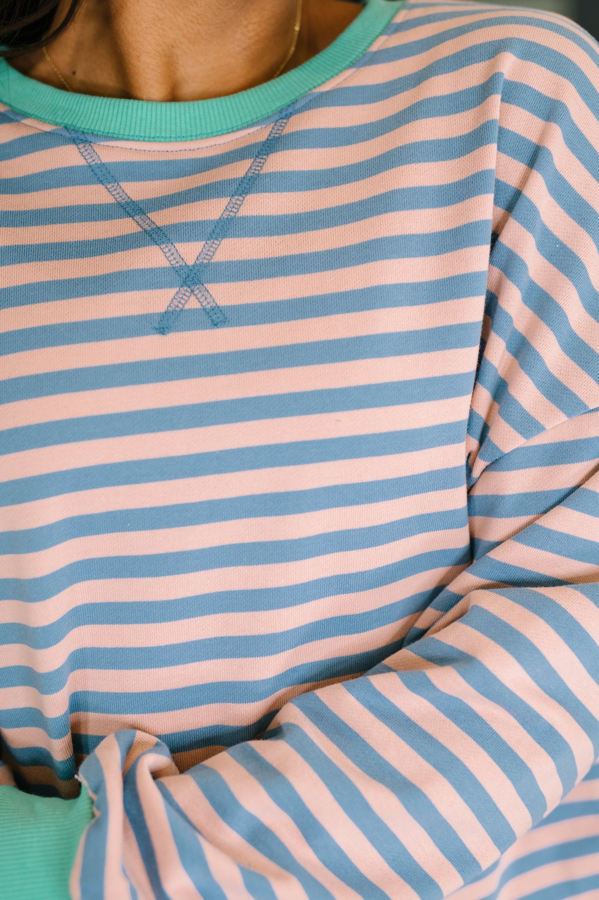 Close-up of a person wearing a striped shirt with pink and blue horizontal stripes.