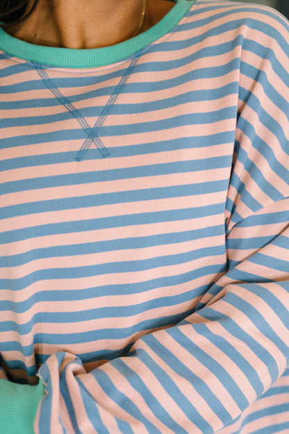 Close-up of a person wearing a striped shirt with pink and blue horizontal stripes.