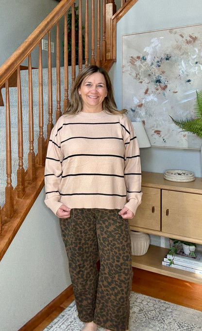 Woman wearing tan and black striped sweater with animal print wide leg cropped jeans