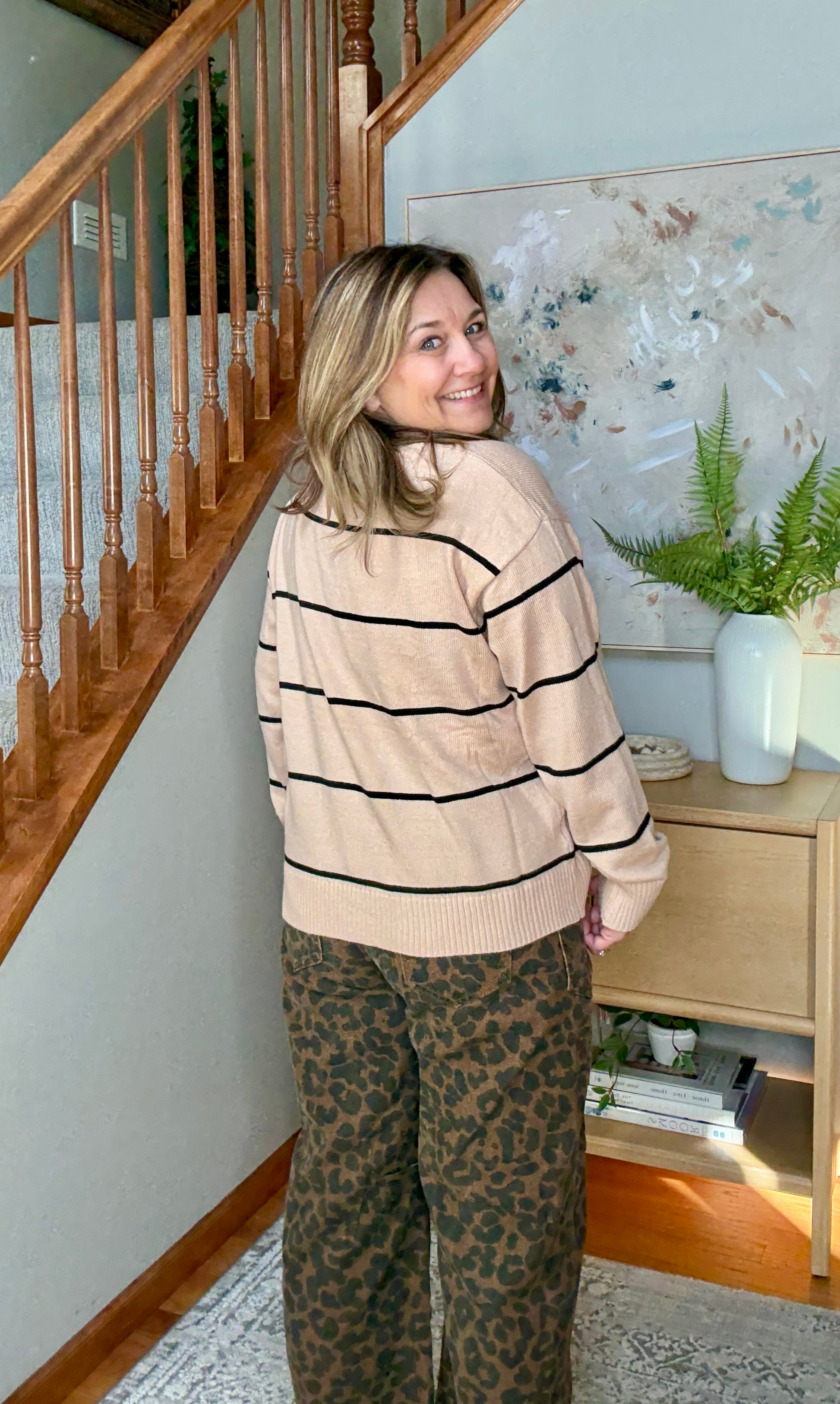 Woman wearing tan and black striped sweater with animal print wide leg cropped jeans from the back