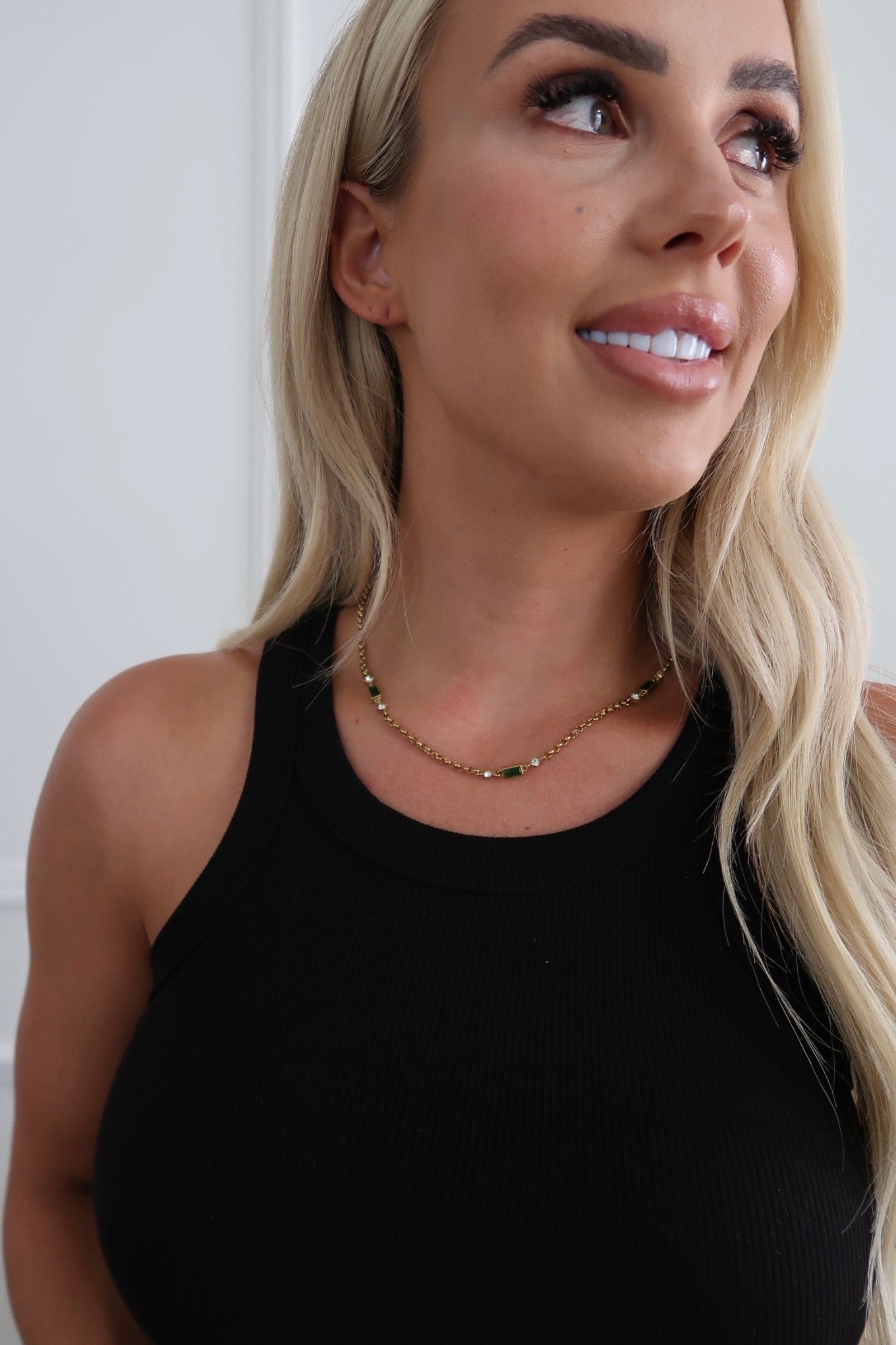 Woman wearing a black sleeveless top with a plain background