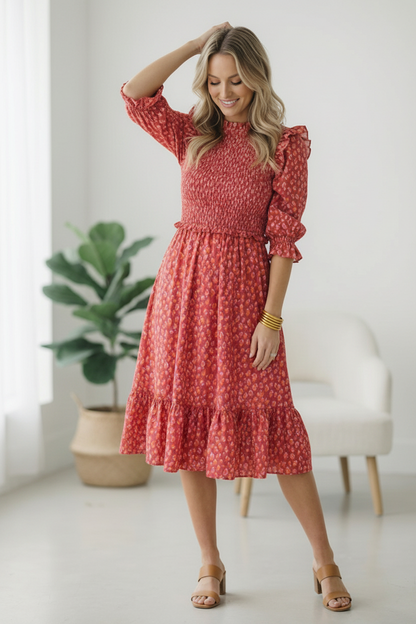 Woman wearing a red dress with a subtle pattern in a bright room.