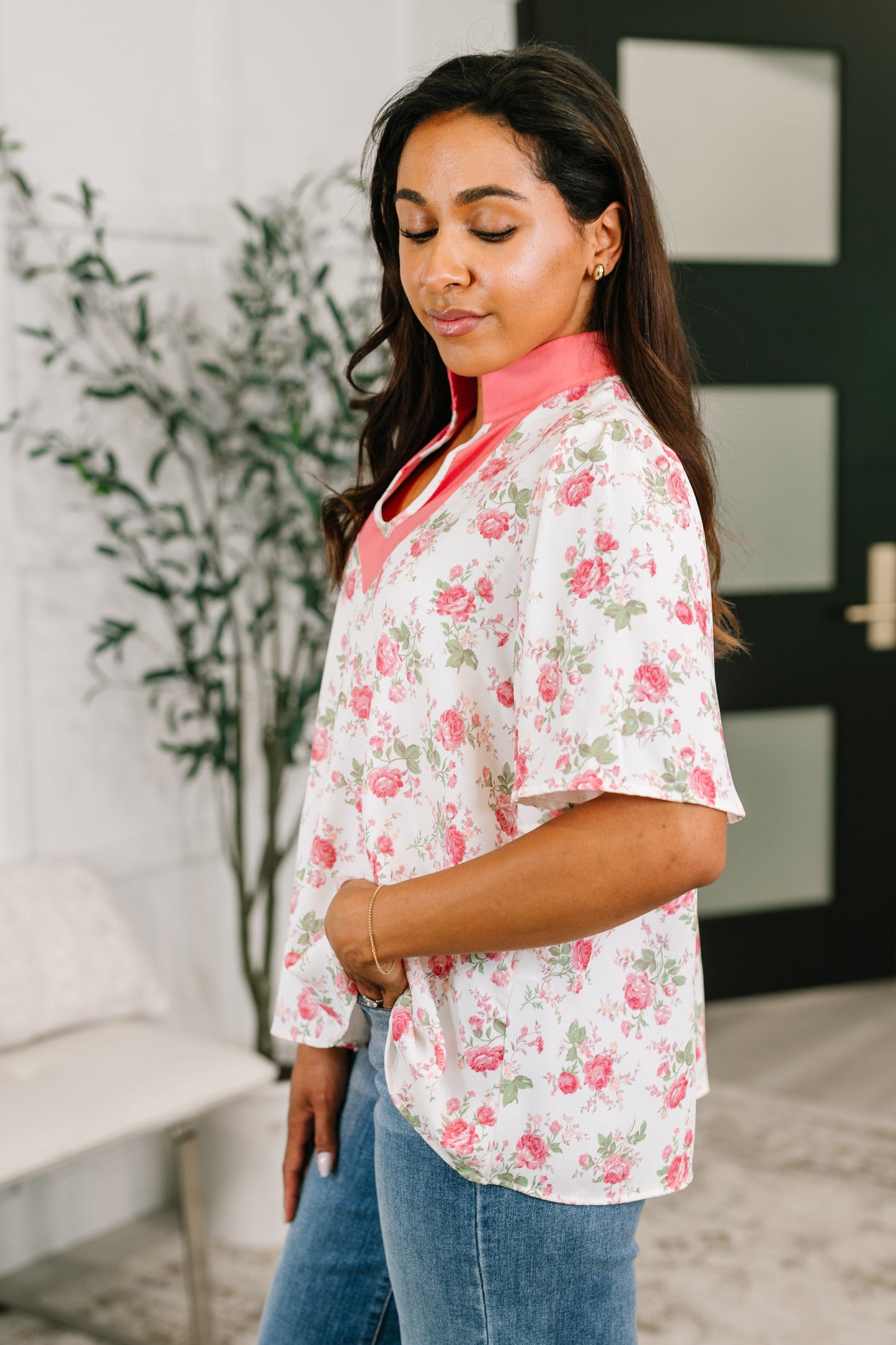 Woman wearing a floral blouse and jeans in an indoor setting